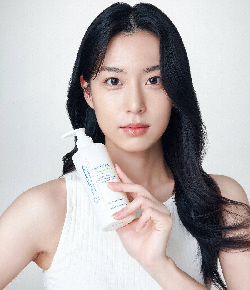 Woman holding a bottle of Age Defying Essence Forte.