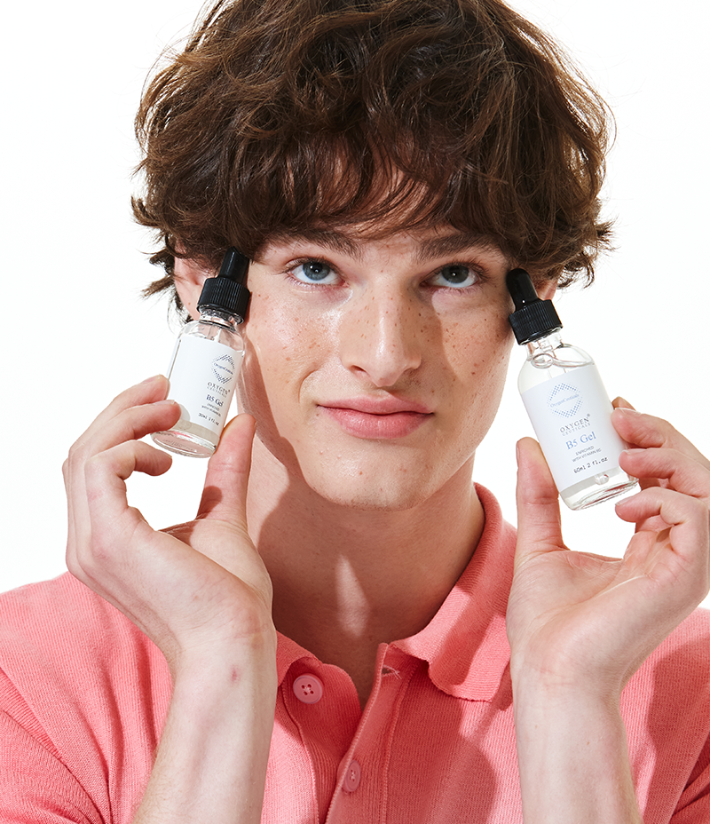 Young man showcasing two bottles of B5 Gel, a hydrating serum with pro-Vitamin B5 complex.