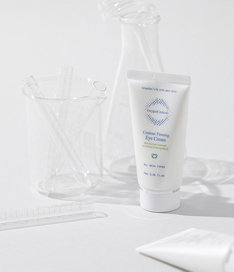 A tube of Contour Firming Eye Cream placed beside a glass beaker showcasing scientific elements. 