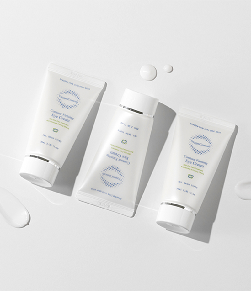 On a white surface, three tubes of hand cream are displayed, specifically designed to combat fine lines and wrinkles called Contour Firming Eye Cream.