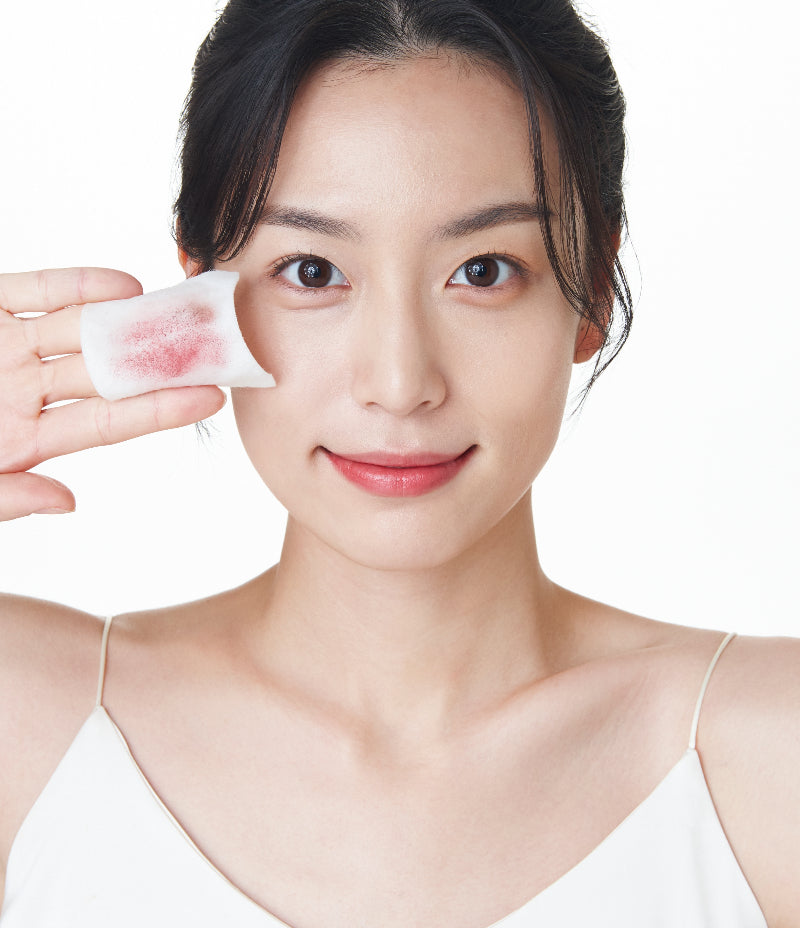 A woman holding up a cotton pad with makeup residue, promoting OxygenCeuticals' Double Makeup Remover, an effective oil cleanser and makeup remover.