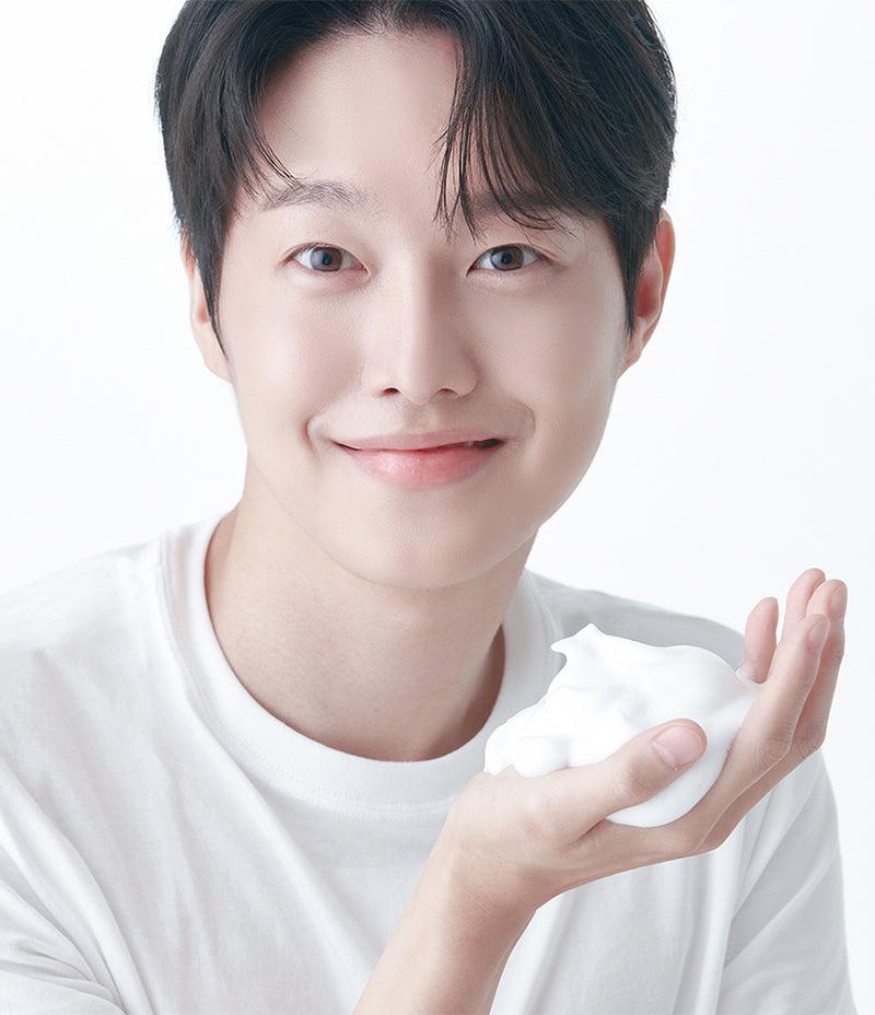 Model Yeonjae holding some Pore Mask foam in his hand while smiling.