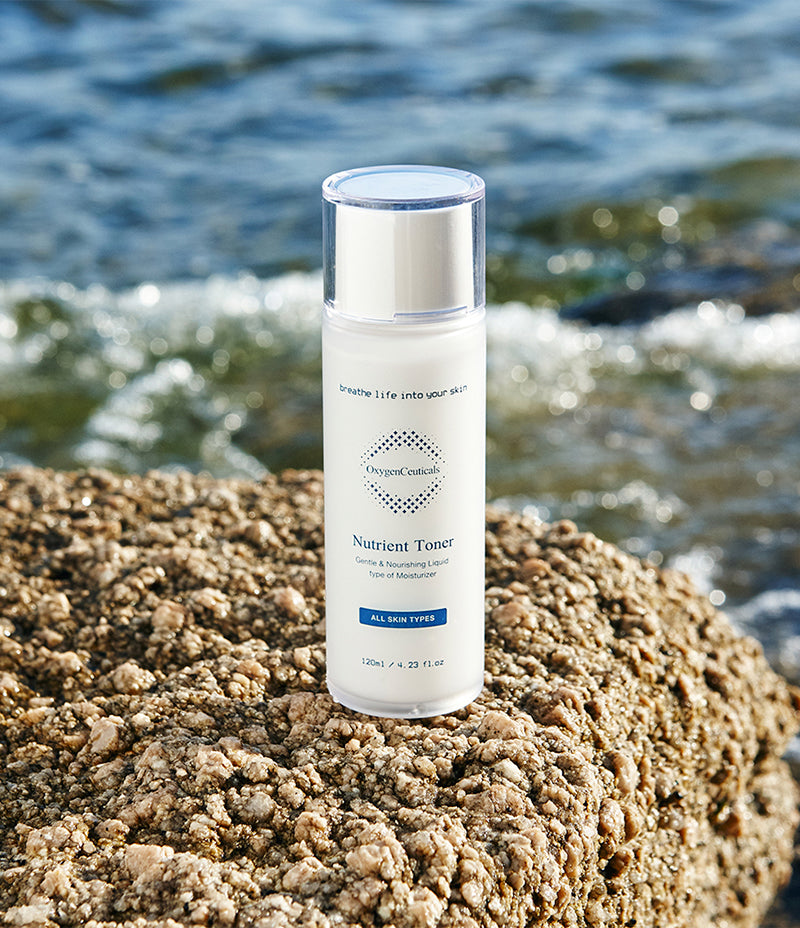 Toning of skin. A bottle of Nutrient Toner placed on a rock by the ocean, reflecting serenity and hydration.