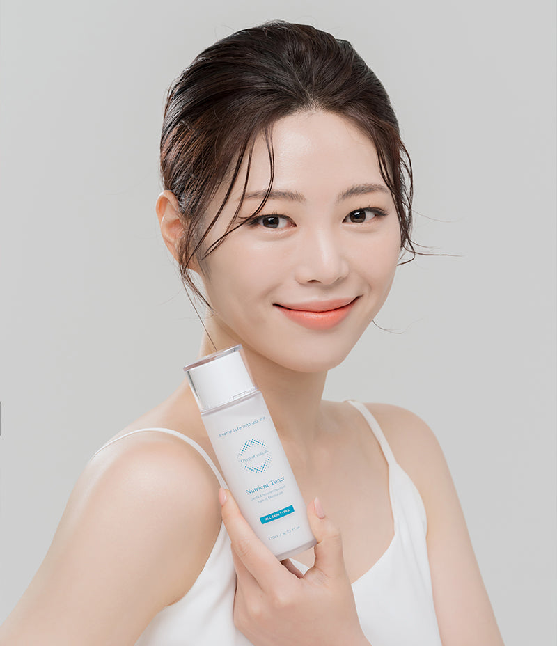 Toning of skin. A woman showcases a bottle of Nutrient Toner, a skin care product, highlighting its potential to nourish and enhance the skin's appearance.