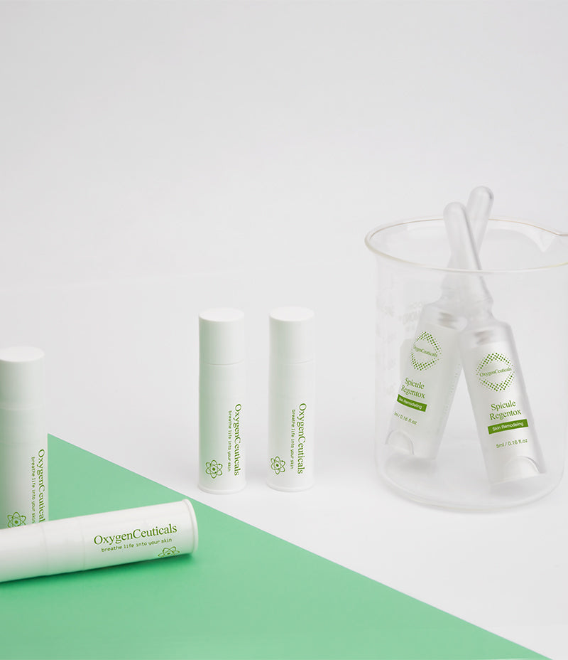 Neckline view of three Spicule Regentox serums, known for enhancing microstimulation of skin activity, artistically arranged on a contrasting green and white surface.