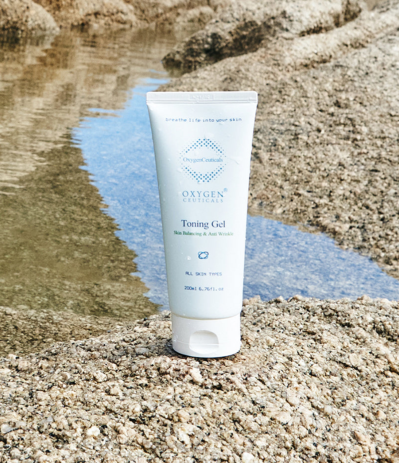 A tube of Toning Gel placed on a rock by the water, ready to soothe your irritated, sensitive skin, for toning of skin, includes ingredients such as cica, centella leaf extract. Oxygen gel.