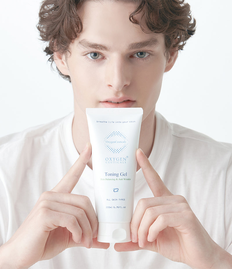 Model Justin holding up a tube of Toning Gel while looking directly into the camera. For toning of skin and includes soothing ingredient such as  centella leaf extract, cica. Oxygen gel.