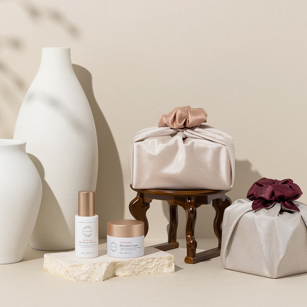 Image showing ReGenon Line, OxygenCeuticals premium anti-aging line, ReGenon Serum, a hydrating and plumping and ReGenon Cream, a moisturizing and hydrating cream, displayed with parcels wrapped in traditional Korean cloth wrapping, to celebrate Mothers Day 