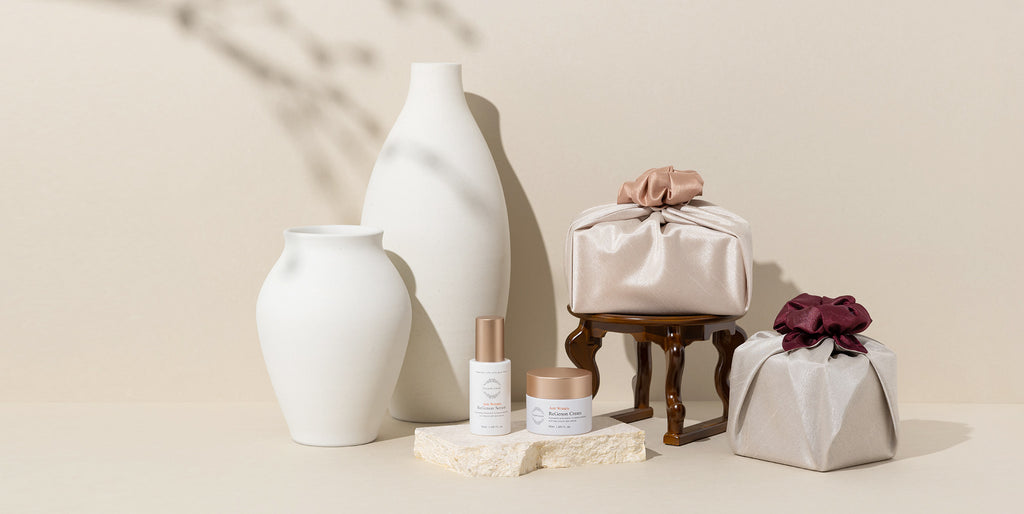 Image showing ReGenon Line, OxygenCeuticals premium anti-aging line, ReGenon Serum, a hydrating and plumping and ReGenon Cream, a moisturizing and hydrating cream, displayed with parcels wrapped in traditional Korean cloth wrapping, to celebrate Mothers Day 