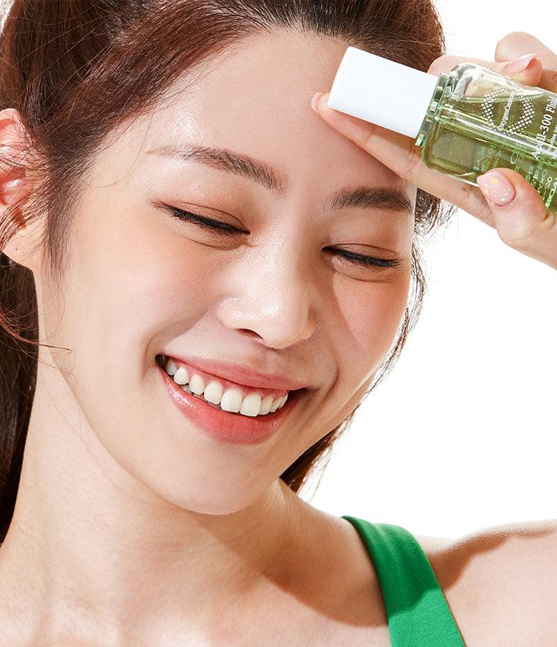 Delighted woman showcasing Acell-300 Fluid for achieving Korean glass skin.