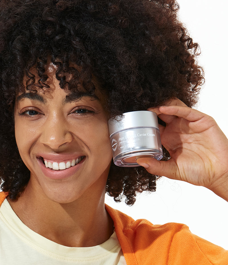 A happy female showcasing her anti-ageing solution, a firming caviar infused cream.