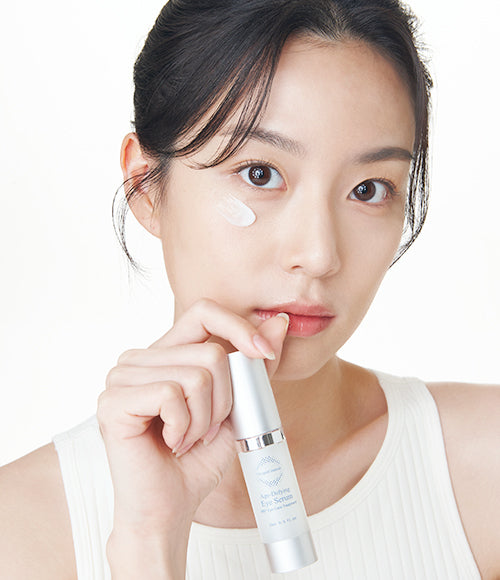 An image featuring a woman holding a tube of eye serum, showcasing the 360 Eye Perfection Duo, a full eye care kit targeting dark circles and wrinkles.
