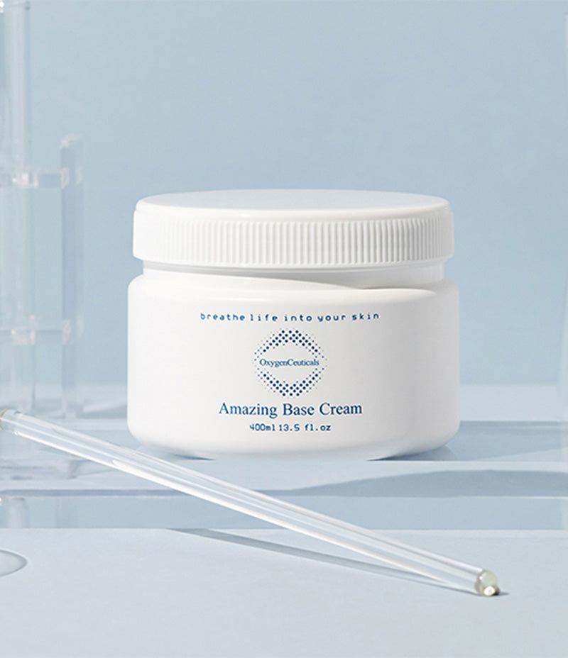  A tub of Amazing Base Cream designed to lock in moisture, elegantly showcased against a soothing pale blue background with scientific glass beakers and test tubes framing the image.