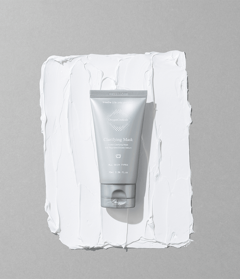 Tube of skin clarifying product lying across a square displaying the creamy texture of the mask.