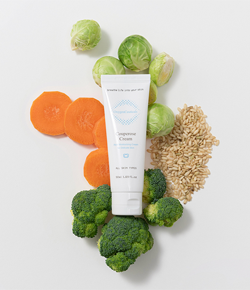Photo of Couperose Cream with a variety of different plants and vegetables to signify its potent blend of seven botanical ingredients.