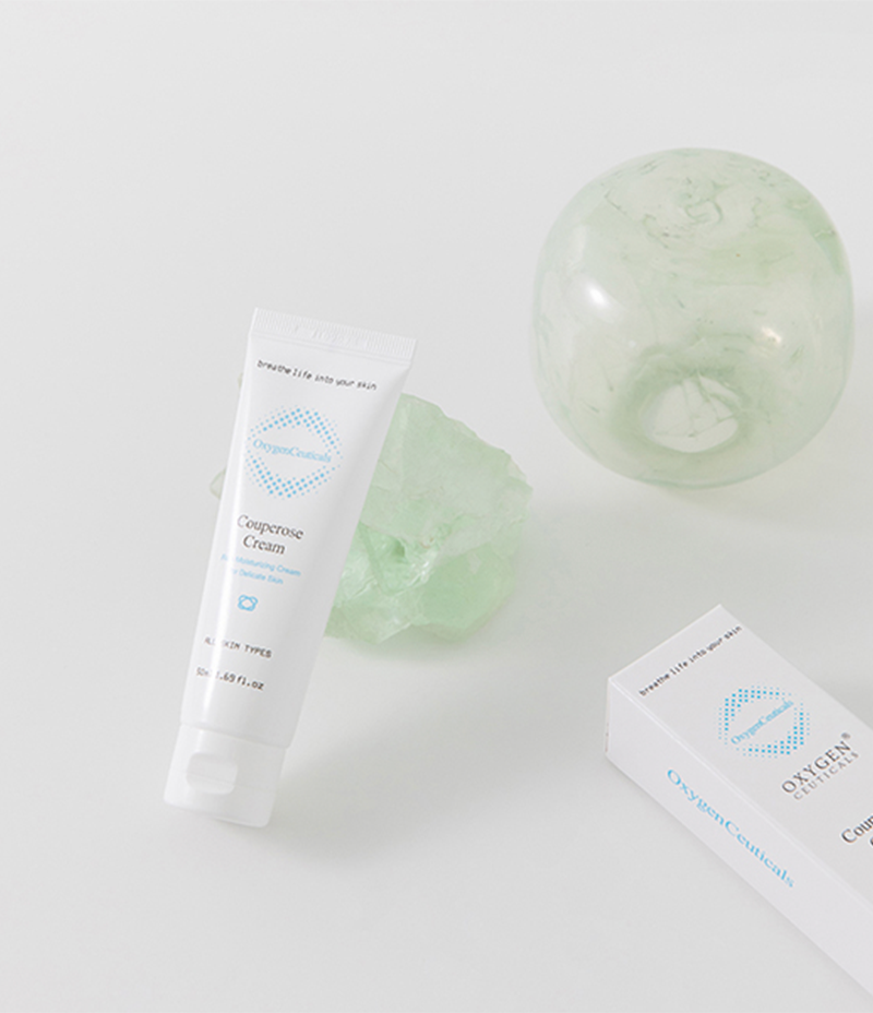 Image showcasing Couperose Cream, a soothing cream for skin, leaning against a distinctive turquoise salt rock and elegant glass ball.