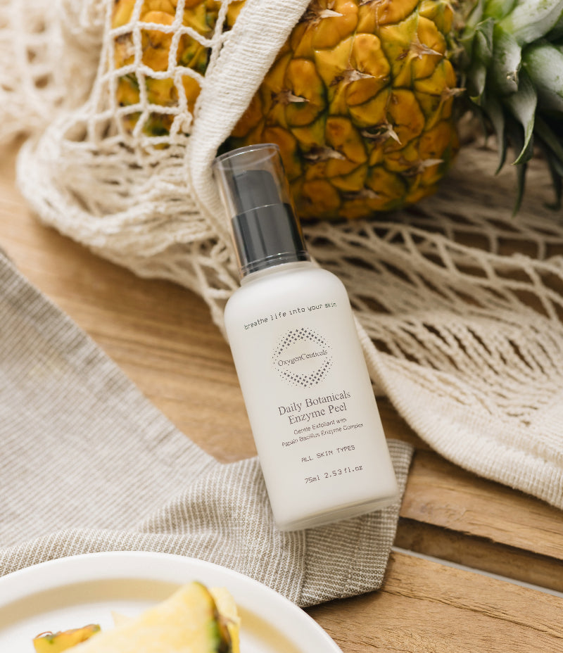 An image of OxygenCeuticals' Daily Botanicals Enzyme Peel, featuring a pineapple on a wooden table.