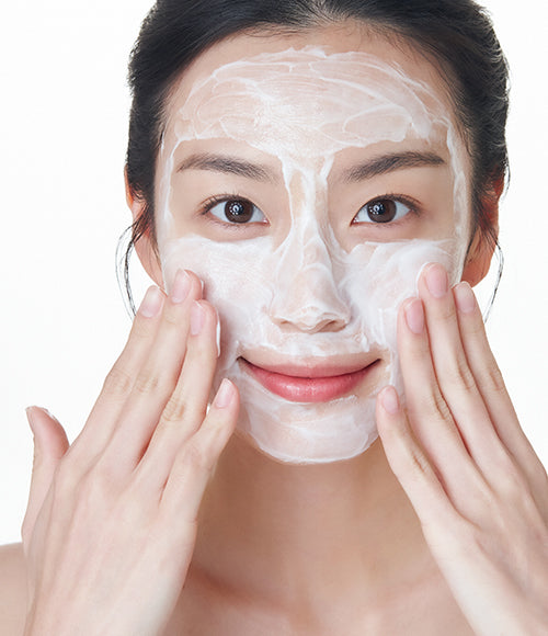 Woman using the Gentle Facial Cleansing Lotion, a non-foaming cleanser, to remove makeup and cleanse her skin.