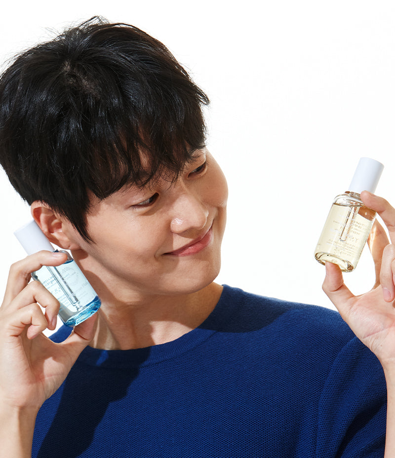 A joyful male model showcasing the soothing Herbal and Couperose Fluid, while expressing happiness.