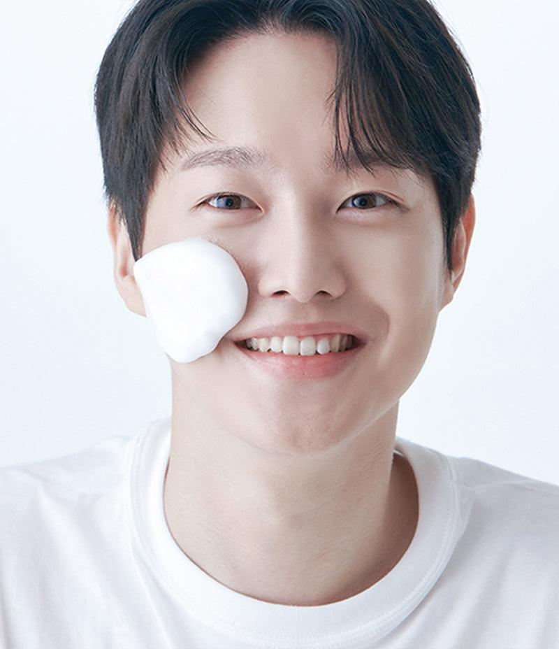 Model Yeonjae smiling with a dab of Pore Mask foam on his cheek