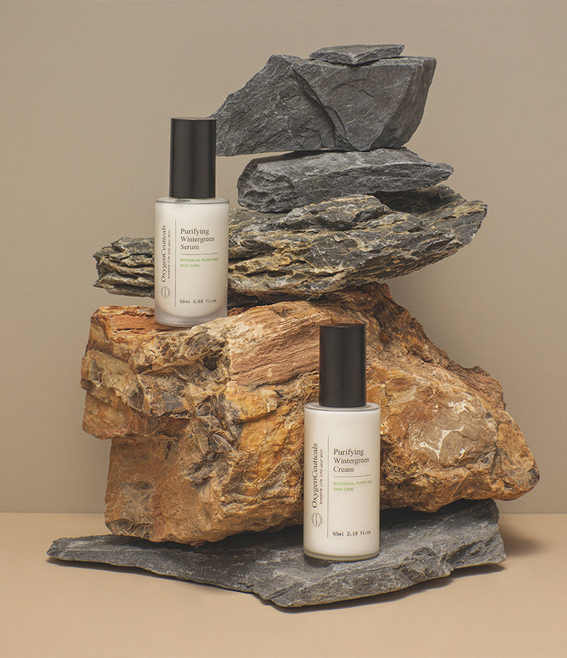A natural skincare products, Purifying Wintergreen Serum and Cream, placed on a stone, ideal for blemished skin treatment.