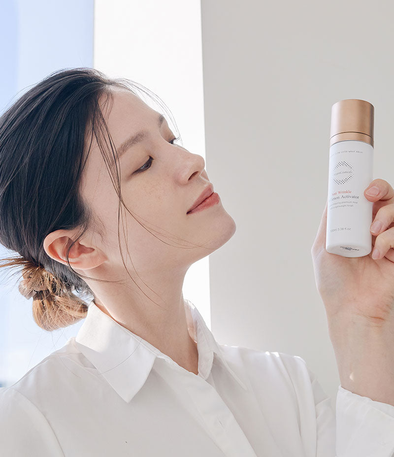 Woman peacefully considering the bottle of ReGenon Activator in her hand in a bright, sunlit room. 