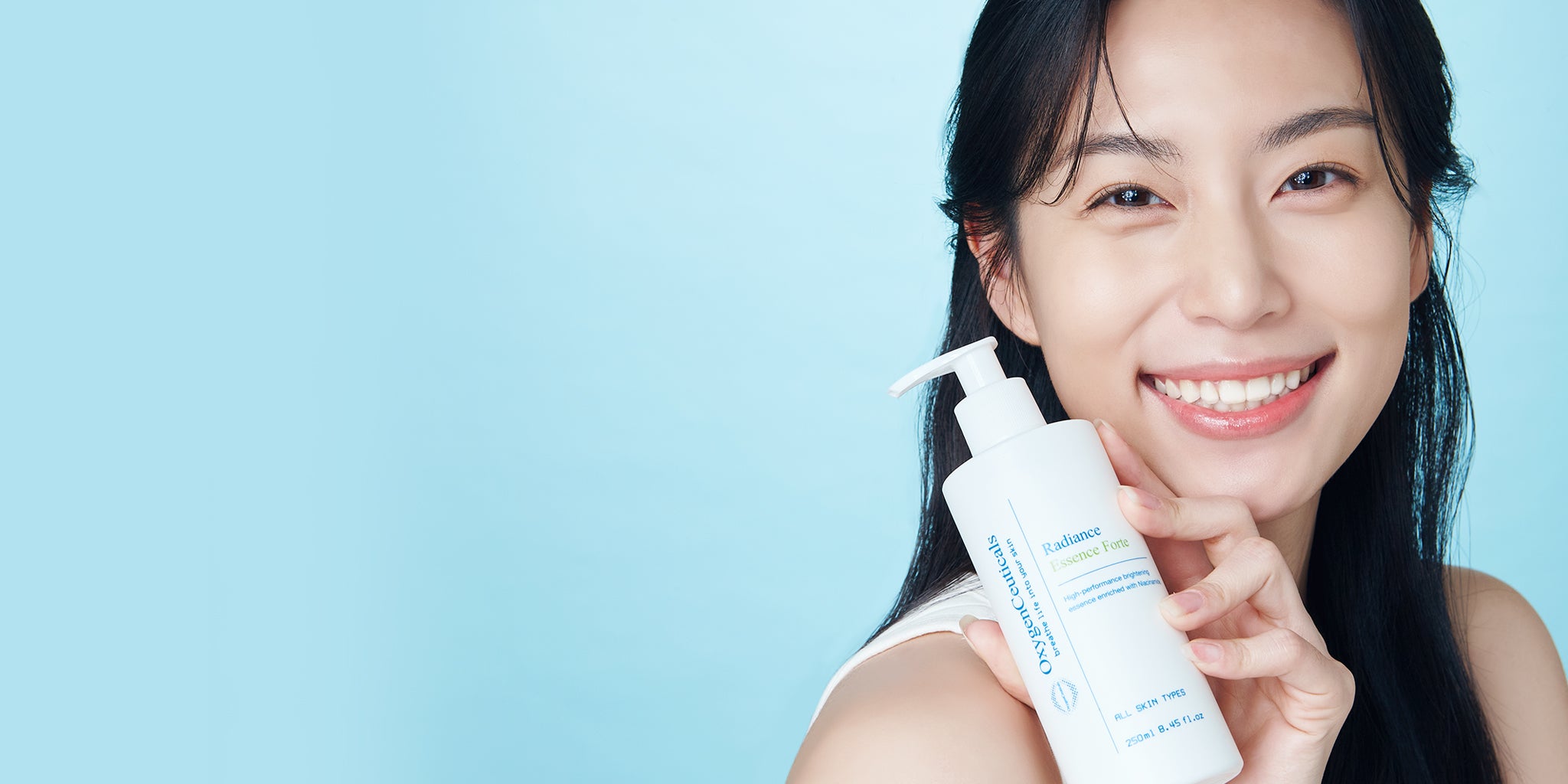 Woman holding Radiance Essence Forte with clear, bright skin and a wide smile.