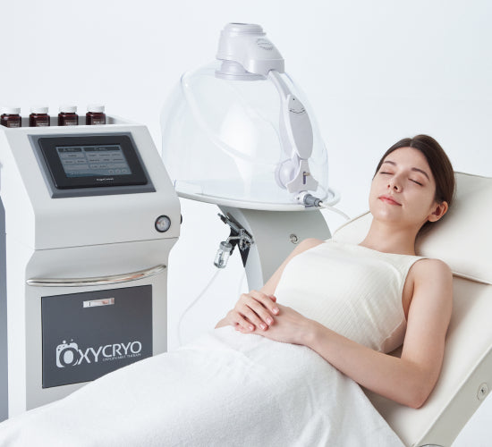Woman lying peacefully on a treatment bed beside two of OxygenCeuticals' best selling represenative devices, the AstrodomeFacial and OxyCryo, best post-procedure oxygen therapy aesthetic solutions.