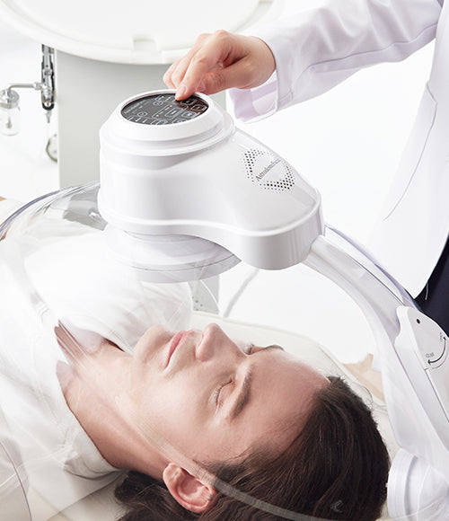 Man with head underneath OxygenCeuticals AstrodomeFacial, LED Skincare Device with Dome.